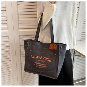 Detail of grey canvas tote bag featuring orange letter print and side view on shoulder