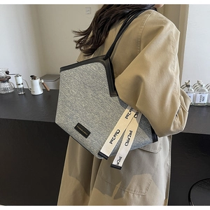 Détail du sac cabas en tweed gris avec garnitures en cuir noir et rubans décoratifs