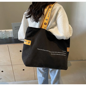 Detail of black canvas tote bag with a distinctive yellow geometric jacquard strap