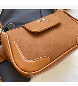Dettaglio della borsa a spalla marrone caramello con cuciture in pelle e camoscio testurizzato
