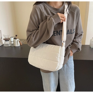 Gros plan sur le sac bandoulière matelassé blanc avec sa sangle large et texture moelleuse