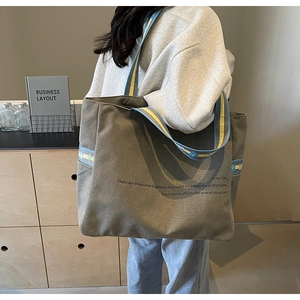 Detail of grey canvas tote bag with floral woven straps and motivational slogan print