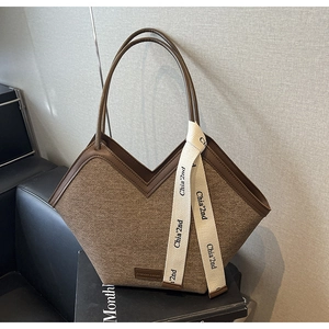 Détail d'un sac cabas en laine marron avec ouverture en V et sangles à lettres tissées