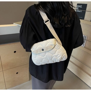 Detail of cream quilted puffer bag showing soft cloud-like texture and wide nylon strap