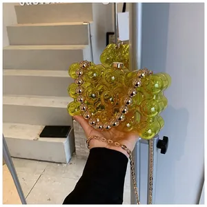 Detail of yellow transparent bubble texture handbag with gold beaded handle and chain