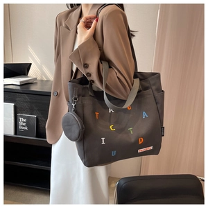 Close-up of grey canvas tote bag with colorful letter embroidery and mini coin purse