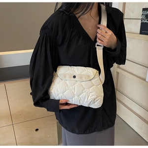 Close-up of white quilted padded shoulder bag with wave stitching and round black buckle