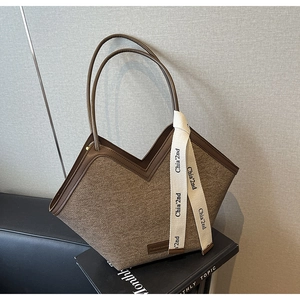 Détail du cabas en feutre marron avec ouverture en V et lanières en cuir sur des livres