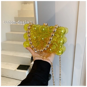 Detail showing neon yellow translucent bag with bubble texture and gold bead handle
