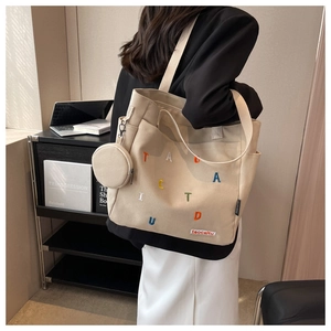 Detail of canvas tote bag featuring colorful letter embroidery and small round coin purse