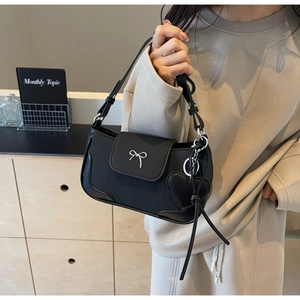 Dettaglio borsa vintage nera con fibbia a fiocco argento e ciondolo a cuore laterale