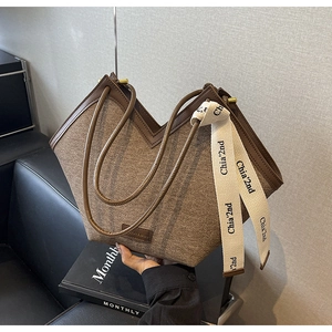 Détail d'un sac cabas en denim texturé avec bordure en cuir marron et ouverture en V