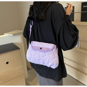 Detail showing purple quilted nylon crossbody bag with diamond stitching and black buckle