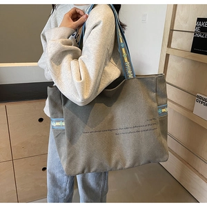 Detailed shot of an olive green canvas tote bag with woven straps and quote print