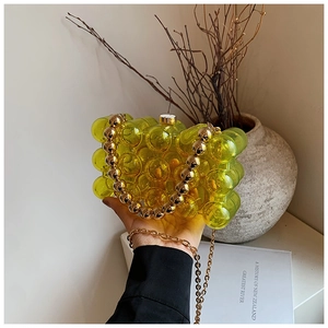 Macro detail of a lemon yellow bubble sphere handbag with a golden bead handle and chain
