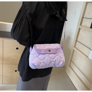 Detailed back view of a light purple quilted shoulder bag on model for size reference
