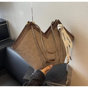 Détail d'un cabas en toile marron avec ouverture en V et ruban décoratif à logo