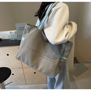 Close-up of grey canvas tote bag featuring geometric patterned strap and text detail