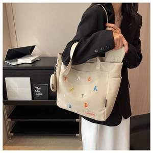Detail of canvas tote bag with letter embroidery and attached round coin purse