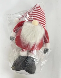 Close-up of a Christmas gnome doll with red striped hat in its clear plastic packaging