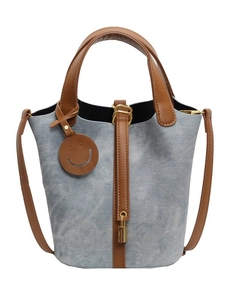 Chic light blue bucket bag with brown handles and gold hardware on white background