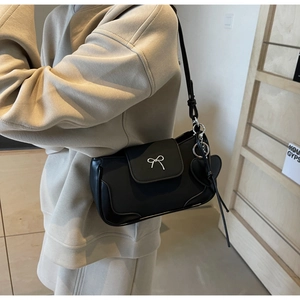 Dettaglio della borsa a spalla nera con fibbia a fiocco argento e ciondolo a cuore