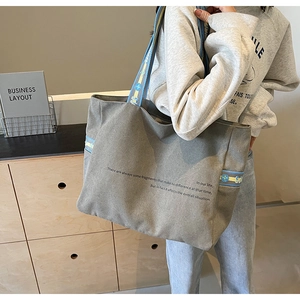 Detail of grey canvas tote bag with floral strap accents and minimalist text print