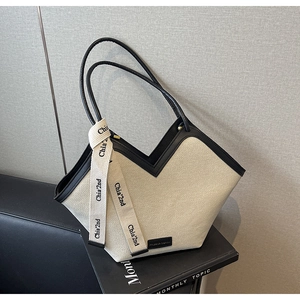 Détail du cabas en toile avec ouverture en V et ruban décoratif sur la bandoulière