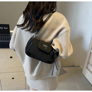 Dettaglio di una borsa a tracolla vintage nera opaca con fiocco bianco e cinturino