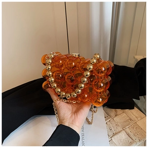 Macro shot of amber bubble handbag with gold beaded handle and fine chain strap details