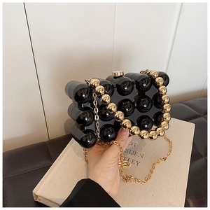 Detail of black pearlescent eggshell evening bag with gold beaded handle and metal chain