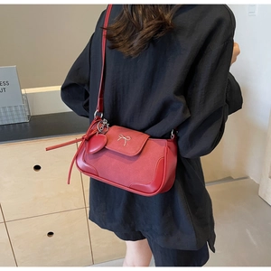 Dettaglio della borsa rossa con fiocco d'argento e ciondolo a cuore su una modella