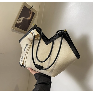 Détail du sac cabas minimaliste en toile crème avec poignées en cuir noir et ouverture en V