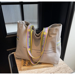 Detail of canvas tote bag with wide colorful woven strap and black graphic print