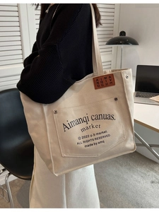 Minimalist beige canvas tote bag with shoulder straps and decorative leather label