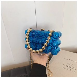 Detailed shot of blue transparent bubble acrylic evening clutch with gold bead handle