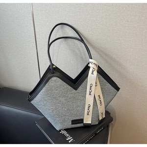 Détail du grand sac cabas en denim avec anses en cuir et ruban logo décoratif