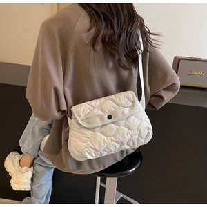 Close-up of white quilted crossbody bag with diamond texture and adjustable strap