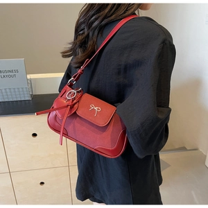 Dettaglio borsa rossa in pelle con fibbia a fiocco argento e ciondolo a cuore su modella