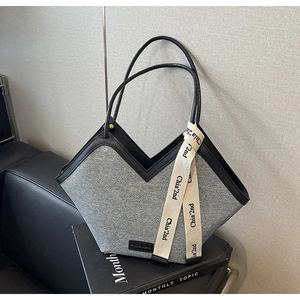 Détail du grand sac cabas en denim gris avec structure en V et bordures en cuir noir