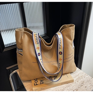 Detail of khaki canvas tote bag featuring red and blue lettered webbing straps