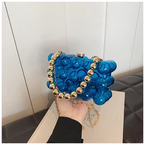 Detail of blue acrylic clutch featuring bubble texture and gold beaded handle