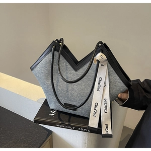 Détail du sac cabas en denim gris avec bordure en cuir noir et ouverture en V