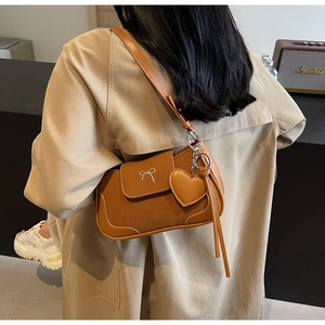 Dettaglio borsa a spalla marrone vintage con fibbia a fiocco e ciondolo a cuore