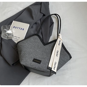 Détail du cabas en tissu gris avec bordure en cuir noir, col en V et longues lanières