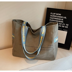 Detail view of olive green canvas tote bag with contrast embroidered strap handles