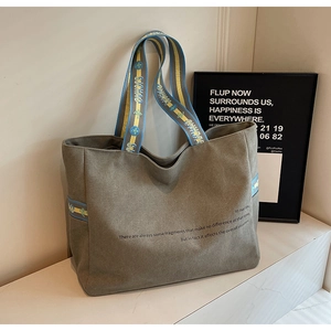 Detail of grey-green canvas tote bag with contrast woven handles on marble surface