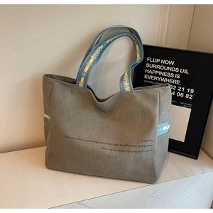 Detail of grey canvas tote bag featuring geometric patterned straps and artistic text