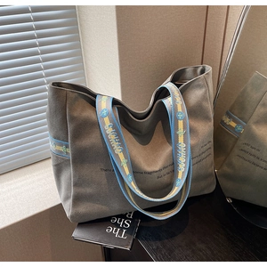 Detail of grey canvas tote featuring embroidered floral straps and minimalist print design