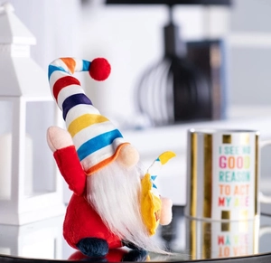 Close-up of a handmade rainbow gnome plush with a colorful striped hat and white beard